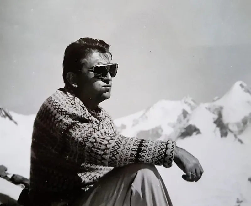 Teresio sitting in the mountains in sunglasses, gazing at the horizon