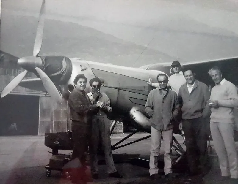 Teresio in front of a propeller aircraft with other people